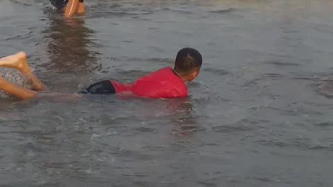 Anak kecil berenang di pantai