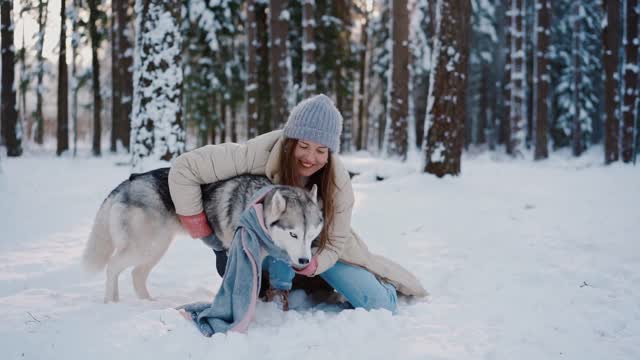 A woman having fun with a dog in the snow