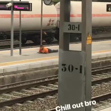 Chill out bro man in orange laying on train platform
