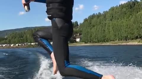 Guy in blue wetsuit jumps off boat and into water