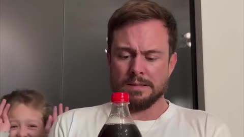 Father and daughter anticipate a soda bottle explosion while adding rubber bands 😳