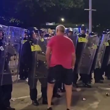 Rioter pushing against police shields is knocked to the ground