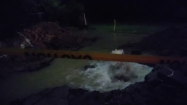 Broken water main, rumbles and flows under streetlight