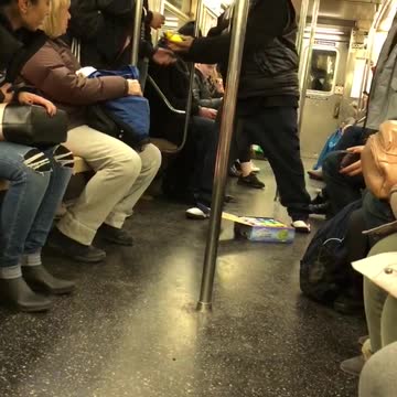 Guys wind up yellow ball and drop it on the floor of subway