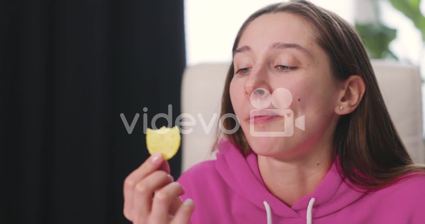 Happy Young Woman Sitting At Desk And Eating Delicious Potato Chips 1