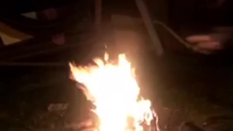 Two guys jump over bonfire