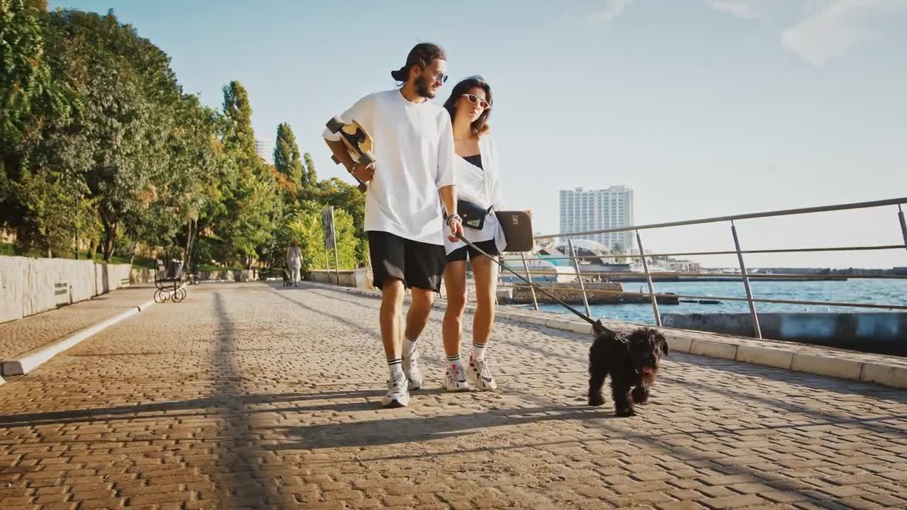 Couple of skaters walking with dog at seafront