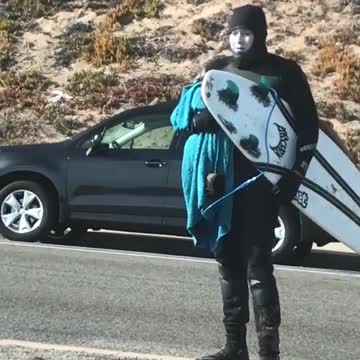 Guy covered in white sunblock grabs board to go surfing
