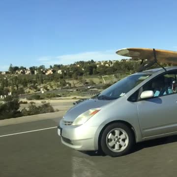 Yellow surfboard on silver prius