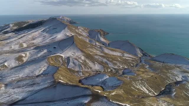 snow topped hills by the ocean