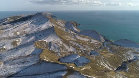 snow topped hills by the ocean