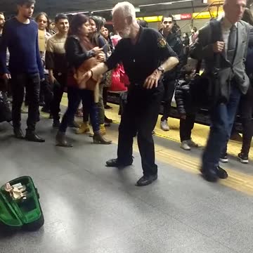 Old man in black dancing in subway station