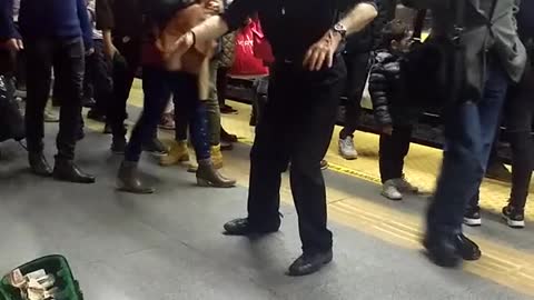 Old man in black dancing in subway station