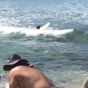 Yellow surfboard kid paddles out in ocean