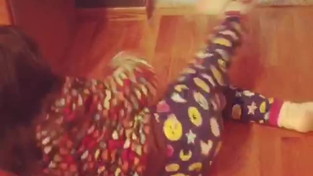 White dog dragging little girl in dotted pajamas away by her sock