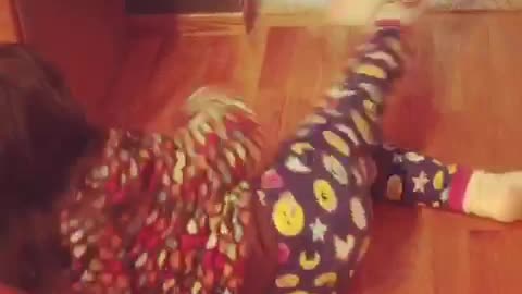 White dog dragging little girl in dotted pajamas away by her sock