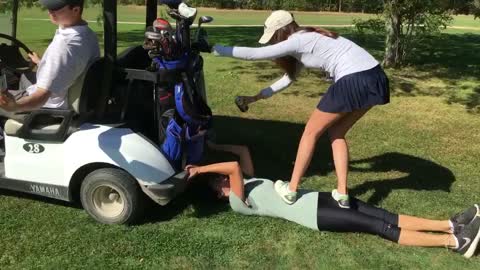 Girl in white on top of guy giving him beer while golf cart is moving