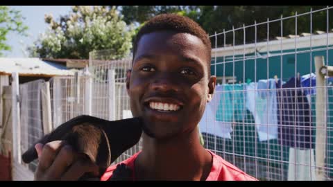 African American volunteer man in a dog shelter with a puppy