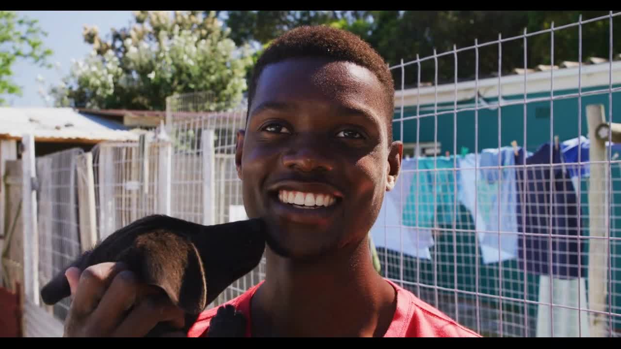 African American volunteer man in a dog shelter with a puppy