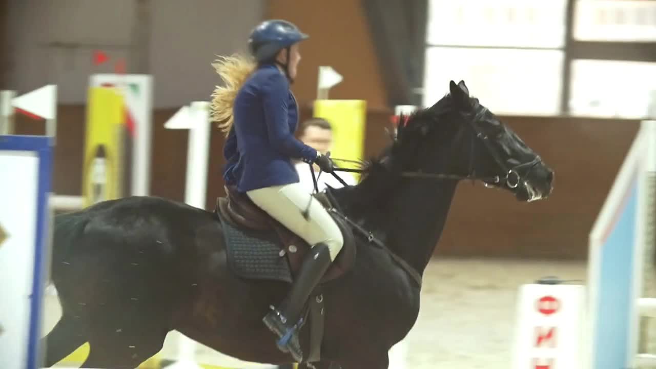 Female rider on the horse jumping over the hurdle at show jumping competition