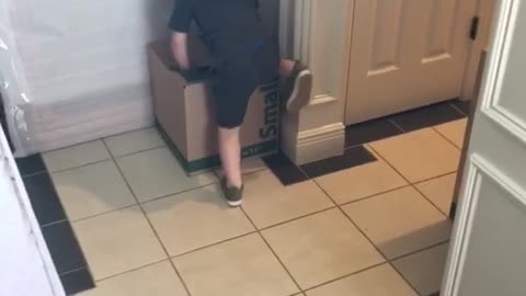 Little kid boy runs to box and tries to climb up gives up then hits head on cabinet door