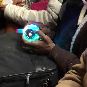 Man holds weird glowing blinking device on subway