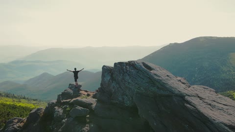 Hiker Stands on a Rock Looking to the Future at Sunset