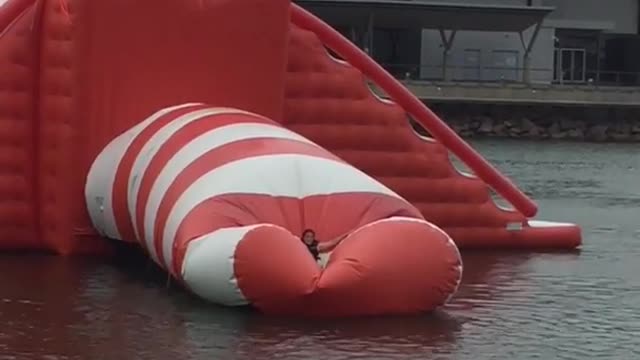 Two girls jump on giant orange balloon