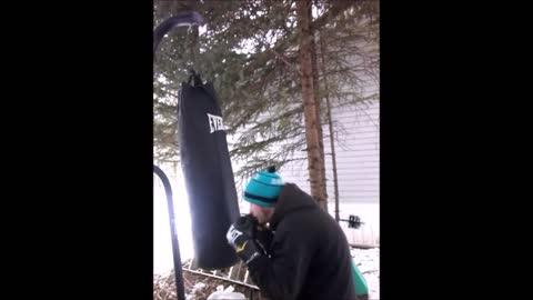 Canadian man hits frozen Everlast 100lbs heavy bag while his cat climbs on the roof