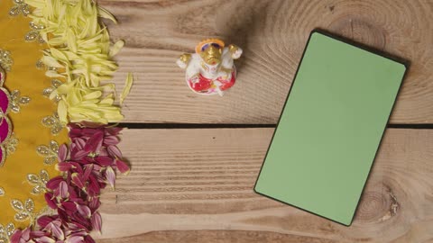 Hand Picking Up Statue Of Ganesh On Table With Green Screen Digital Tablet In Festival Of Diwali