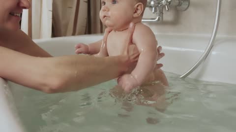 Mother playing with her baby in a tub of water