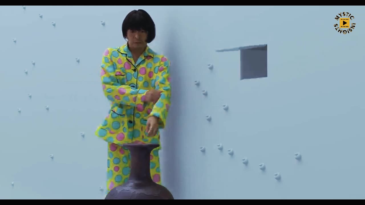 Japanese man locked in an unfurnished room, the walls adorned with an array of random button