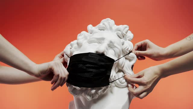 People Placing A Face Mask On A Sculpture Then Falls Off