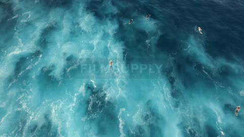 People travel in the blue water below on surfboards