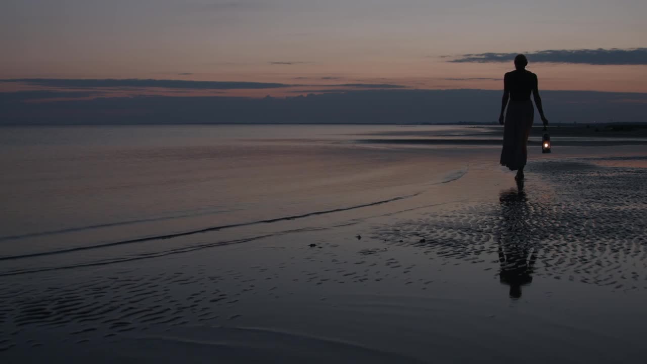 Woman walking on beach with lantern