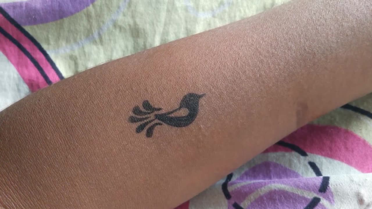 Making bird tattoo on hand with pen