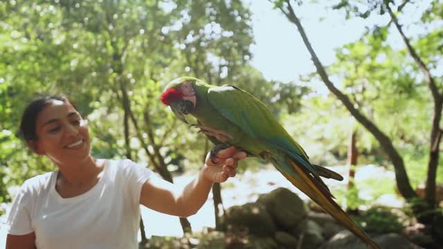 A woman talking to her parrot while feeding it