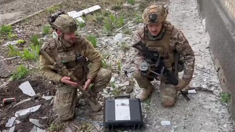 Ukrainian soldiers pick up a box from a drone after the house it was in was hit by Russian artillery