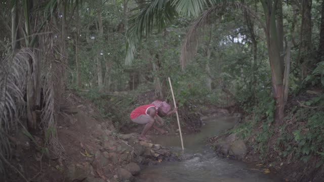 The African man wide shoot super low motion fishing with a stick in pond