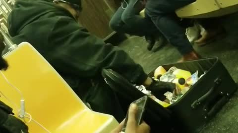 Man opens black suitcase in subway