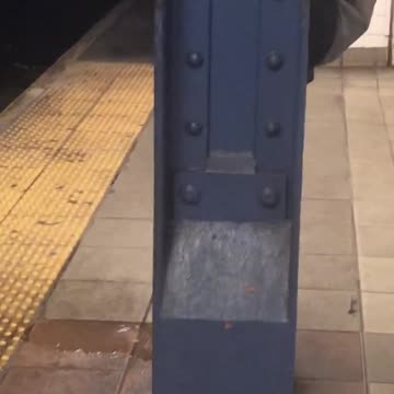 Man peeing behind a metal pillar at subway station