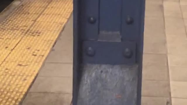 Man peeing behind a metal pillar at subway station