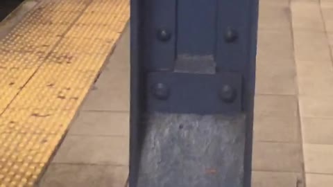 Man peeing behind a metal pillar at subway station