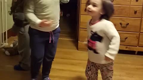 Three kids spin around on wood floor one falls down