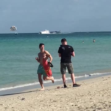 Blue shorts guy running past camera with red floating raft