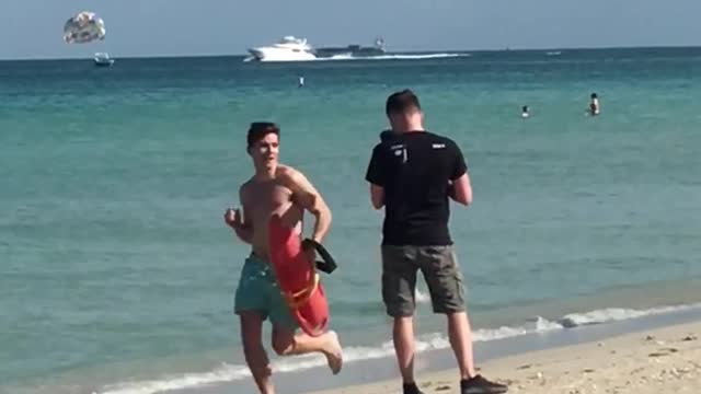 Blue shorts guy running past camera with red floating raft