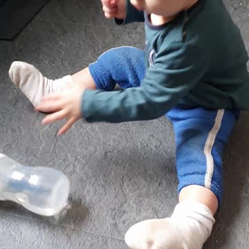 Baby boy are trying to drink water from bottle by himself