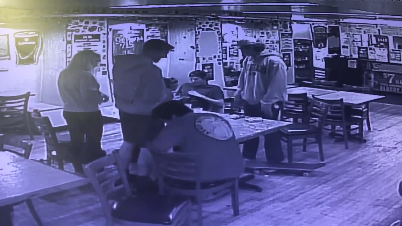 Security camera recording of guy in sweater falling backwards and hitting his head on a table