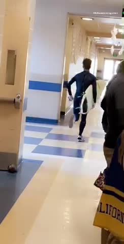 Man black wet suit runs with surf board in hallway