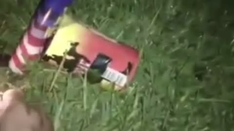 Guy lights firework on grass